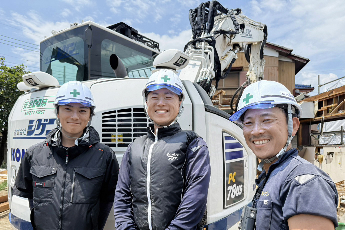 解体現場で肩を組み、笑顔を見せる3人の作業員(仕事のイメージ)